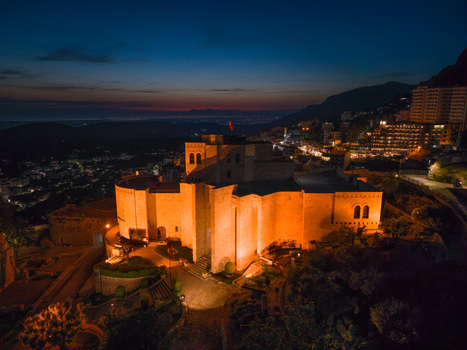 Aerial view of the illuminated Kruje Castle at dusk with city lights and mountain silhouettes in Kruje Durres County Albania.