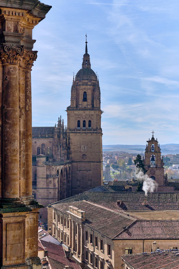 Salamanca Spain 01 December 2025 View of the New Cathedral of Salamanca tower rising above historic rooftops under a blue sky with light clouds. Salamanca Spain 01 December 2025 View of the New Cathedral of Salamanca tower rising above historic rooftops under a blue sky with light clouds.