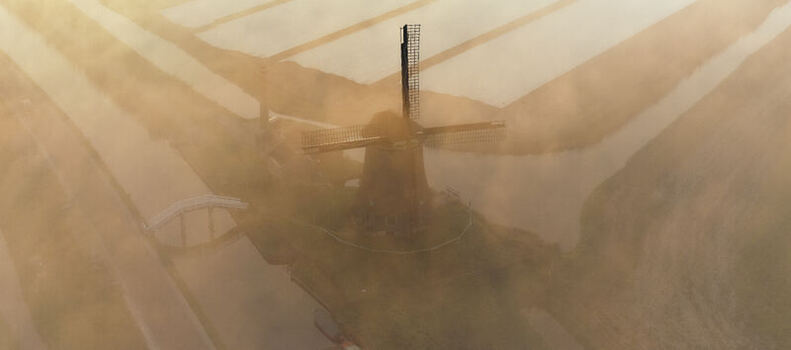 Aerial view of De Kaagmolen windmill surrounded by misty polder fields and canals at sunrise in Spanbroek North Holland Netherlands. Aerial view of De Kaagmolen windmill surrounded by misty polder fields and canals at sunrise in Spanbroek North Holland Netherlands.
