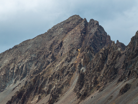 Aerial view of the rugged peak of Mount Sneffels in the San Juan Mountain Range showcasing steep rocky slopes and dramatic formations under a cloudy sky in Ouray Colorado United States. Aerial view of the rugged peak of Mount Sneffels in the San Juan Mountain Range showcasing steep rocky slopes and dramatic formations under a cloudy sky in Ouray Colorado United States.