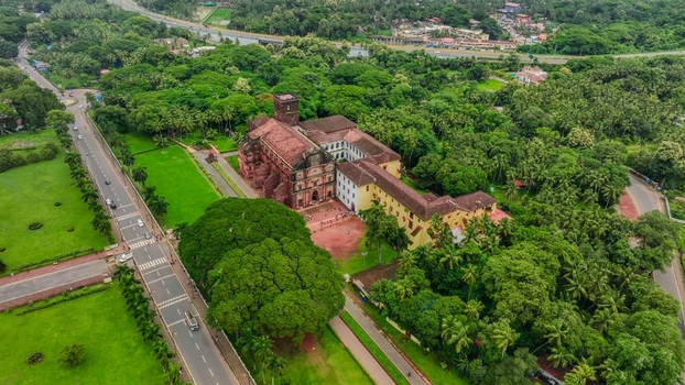Aerial view of the Church of St. Francis of Assisi surrounded by lush green trees palm groves and winding roads in Old Goa Goa India. Aerial view of the Church of St. Francis of Assisi surrounded by lush green trees palm groves and winding roads in Old Goa Goa India.