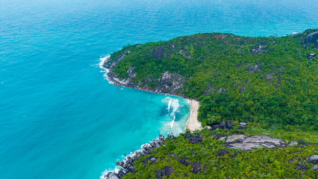 Aerial view of Cap Ternay featuring lush tropical vegetation rocky coastal cliffs and turquoise waters along the shoreline in Cap Ternay Port Glaud Seychelles. Aerial view of Cap Ternay featuring lush tropical vegetation rocky coastal cliffs and turquoise waters along the shoreline in Cap Ternay Port Glaud Seychelles.