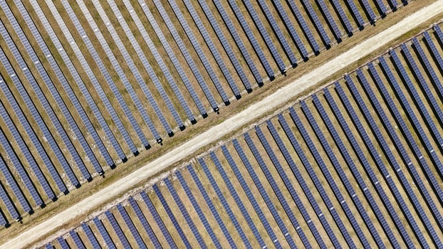 Aerial view of solar panels reflecting the bright sky divided by a sandy path creating a stark contrast between technology and nature Elkton Florida United States. Aerial view of solar panels reflecting the bright sky divided by a sandy path creating a stark contrast between technology and nature Elkton Florida United States.