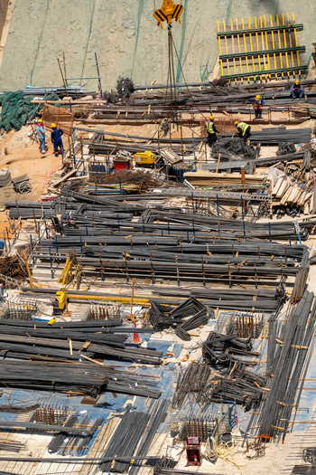 Aerial view of construction workers in safety gear organizing steel rebar and scaffolding at a busy building site in Dubai Dubai United Arab Emirates. Aerial view of construction workers in safety gear organizing steel rebar and scaffolding at a busy building site in Dubai Dubai United Arab Emirates.