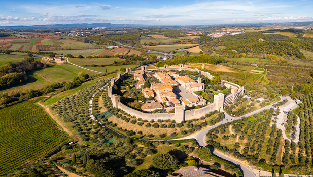 Aerial view of the medieval walled town of Monteriggioni surrounded by olive groves and vineyards in the rolling hills of Tuscany Monteriggioni Tuscany Italy.