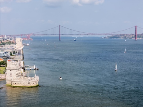 Aerial view of the historic Belem Tower situated on the Tagus River bank with the iconic 25 April Bridge spanning the water in the background in Lisbon Lisbon Portugal.