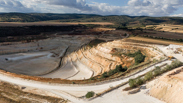 Aerial view of the open pit quarry showing terraced excavation levels white limestone soil surrounding fields and rolling hills under a cloudy sky in Besenovo Vojvodina Serbia. Aerial view of the open pit quarry showing terraced excavation levels white limestone soil surrounding fields and rolling hills under a cloudy sky in Besenovo Vojvodina Serbia.
