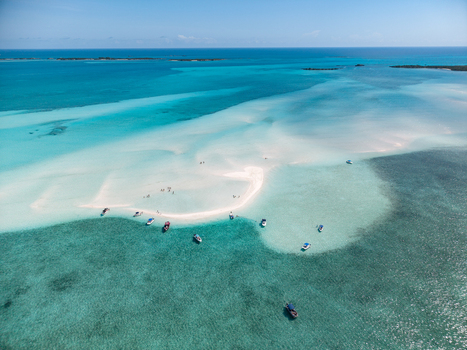 Aerial view of Man O War Cay Sandbar with turquoise water anchored boats and people on the white sand under a clear blue sky in Rolletown Exuma The Bahamas. Aerial view of Man O War Cay Sandbar with turquoise water anchored boats and people on the white sand under a clear blue sky in Rolletown Exuma The Bahamas.