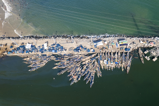 Aerial view of fishing boats clustered tightly along the pier contrasting with the dark water and the sandy beach Tema Ghana. Aerial view of fishing boats clustered tightly along the pier contrasting with the dark water and the sandy beach Tema Ghana.