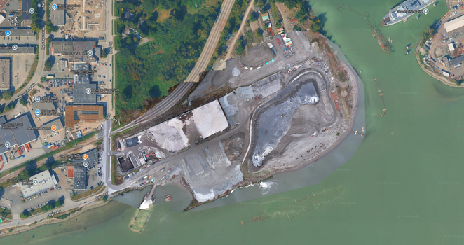 Aerial view of an industrial aggregate processing facility with stockpiles of gravel industrial buildings and access roads along the riverbank in Richmond British Columbia Canada. Aerial view of an industrial aggregate processing facility with stockpiles of gravel industrial buildings and access roads along the riverbank in Richmond British Columbia Canada.