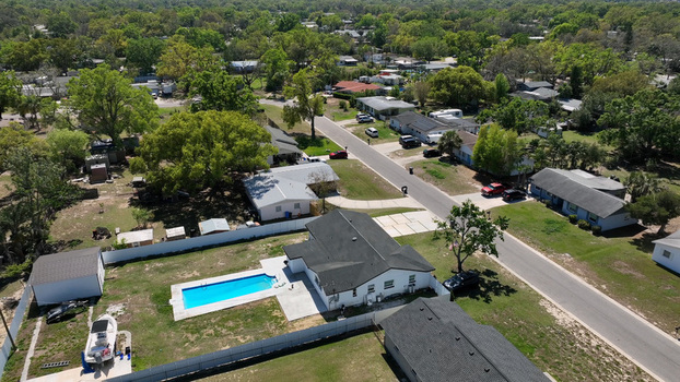 Aerial view of a residential neighborhood featuring single family homes a backyard swimming pool lush green trees and paved streets in Brandon Florida United States.