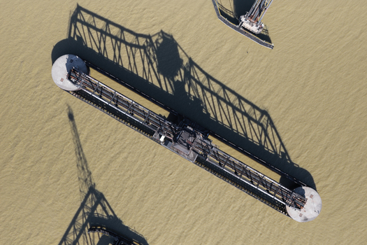 Aerial view of a metal bridge structure spanning over the water with long shadows cast on the surface in Toledo Ohio United States.