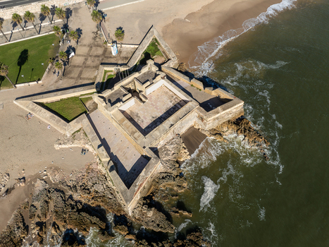 Aerial view of the historic star shaped Forte de Sao Bruno situated on the rocky coastline next to a sandy beach in Caxias Lisbon Portugal.