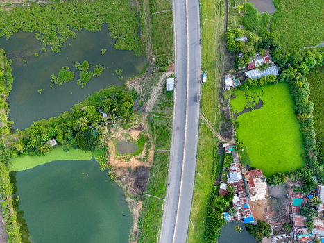 Aerial view of Kalurghat New River view Road passing through lush green landscape with algae covered ponds and small residential buildings in Chattogram Chittagong Division Bangladesh.