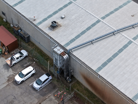 Melbourne VIC Australia 25 September 2026 Aerial view of a factory building featuring a large metal ventilation system on the exterior wall adjacent to a parking lot with several cars.