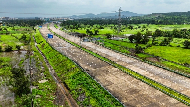 Aerial view of the Delhi Mumbai Expressway stretching through the lush green monsoon landscape with concrete lanes and surrounding vegetation in Badlapur Maharashtra India. Aerial view of the Delhi Mumbai Expressway stretching through the lush green monsoon landscape with concrete lanes and surrounding vegetation in Badlapur Maharashtra India.