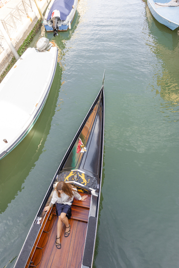 Venice Veneto Italy 21 September 2026 View of a woman sitting in a traditional black gondola floating on a canal in Venice with other boats moored nearby. Venice Veneto Italy 21 September 2026 View of a woman sitting in a traditional black gondola floating on a canal in Venice with other boats moored nearby.