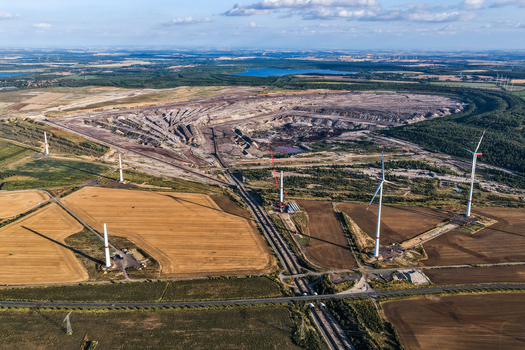 Aerial view of the lignite open cast mine Schleenhain with wind turbines and agricultural fields in the rural landscape of Zwenkau Saxony Germany.