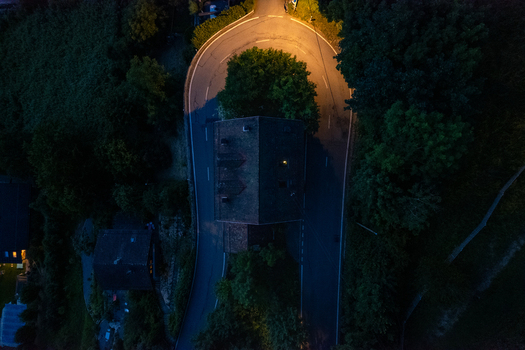 Aerial view of the sharp hairpin turn in Glion illuminated by streetlights at night with a house nestled in the curve surrounded by trees in Montreux Vaud Switzerland. Aerial view of the sharp hairpin turn in Glion illuminated by streetlights at night with a house nestled in the curve surrounded by trees in Montreux Vaud Switzerland.