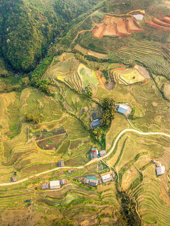 Aerial view of terraced rice fields in the mountainous landscape with winding rural roads small houses and lush green hills in Vietnam. Aerial view of terraced rice fields in the mountainous landscape with winding rural roads small houses and lush green hills in Vietnam.