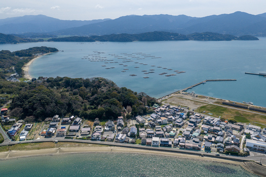 Aerial view of the Itoshima Peninsula featuring a coastal village oyster farming rafts in the bay and lush green hills under a clear sky Itoshima Fukuoka Japan. Aerial view of the Itoshima Peninsula featuring a coastal village oyster farming rafts in the bay and lush green hills under a clear sky Itoshima Fukuoka Japan.