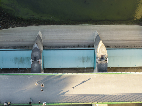 Aerial view of the earth dam on Czorsztyn Reservoir with people walking on the bridge and calm water in Niedzica Wojewodztwo malopolskie Poland.