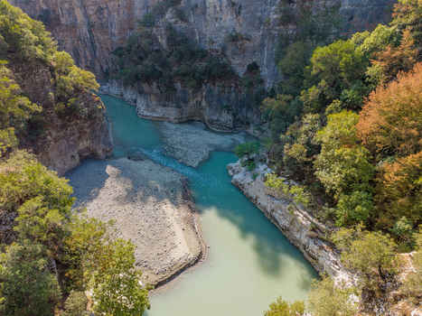 Aerial view of Osumi canyon with its turquoise river flowing through steep rocky cliffs and lush green forests in Dhores Berat County Albania.