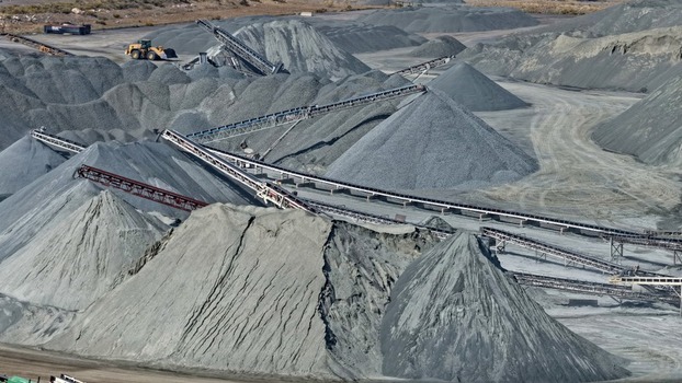 Aerial view of a large industrial quarry featuring massive piles of crushed stone and gravel with complex conveyor belt systems for material processing in Golden Colorado United States.