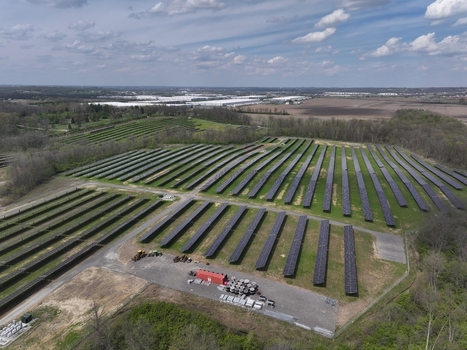 Lebanon United States 12 April 2026 Aerial view of a large solar panel array surrounded by green fields and dense woodland under a cloudy sky.