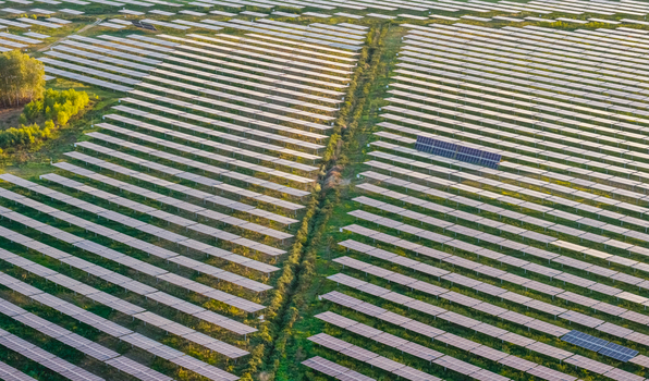 Aerial view of an expansive solar farm with rows of photovoltaic panels creating geometric patterns across a green landscape in Italy. Aerial view of an expansive solar farm with rows of photovoltaic panels creating geometric patterns across a green landscape in Italy.