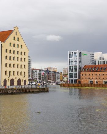 View of the historic waterfront along the Motlawa River with traditional brick buildings and modern architecture reflecting in the water in Gdansk Pomeranian Voivodeship Poland. View of the historic waterfront along the Motlawa River with traditional brick buildings and modern architecture reflecting in the water in Gdansk Pomeranian Voivodeship Poland.