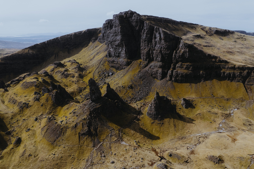 Aerial view of The Storr a dramatic rocky landscape with jagged basalt pinnacles and grassy slopes in Portree Scotland United Kingdom. Aerial view of The Storr a dramatic rocky landscape with jagged basalt pinnacles and grassy slopes in Portree Scotland United Kingdom.