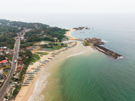 Aerial view of fishing boats lined up on the sandy beach near a rocky breakwater and coastal road Dodanduwa Southern Province Sri Lanka. Aerial view of fishing boats lined up on the sandy beach near a rocky breakwater and coastal road Dodanduwa Southern Province Sri Lanka.