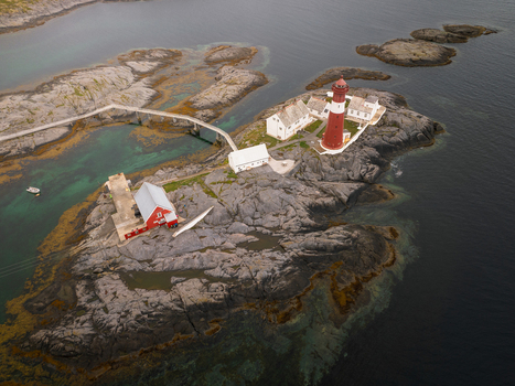 Aerial view of Tranoy Lighthouse situated on a rocky island with red buildings a footbridge and clear coastal waters in Tranoy Nordland Norway. Aerial view of Tranoy Lighthouse situated on a rocky island with red buildings a footbridge and clear coastal waters in Tranoy Nordland Norway.