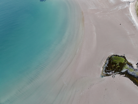 Aerial view of the turquoise waters and sandy shores of Gruinard Bay with gentle ripples and a small rocky islet Gruinard Scotland United Kingdom. Aerial view of the turquoise waters and sandy shores of Gruinard Bay with gentle ripples and a small rocky islet Gruinard Scotland United Kingdom.
