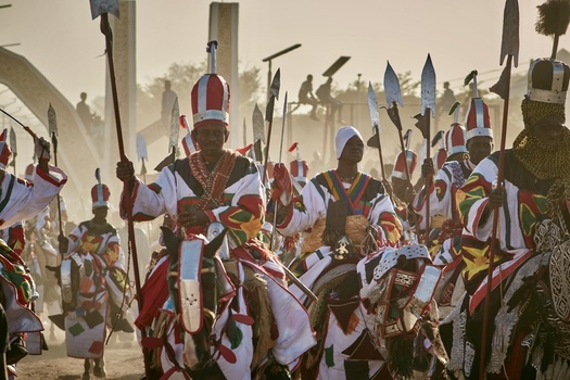 Zaria city Nigerian 21 March 2026 View of a vibrant procession of horsemen in resplendent traditional regalia their colorful garments and gleaming spears vivid against the dusty warm light. Zaria city Nigerian 21 March 2026 View of a vibrant procession of horsemen in resplendent traditional regalia their colorful garments and gleaming spears vivid against the dusty warm light.