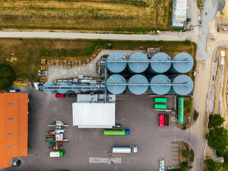 Aerial view of the Neuenstein Techno Zone industrial facility featuring large metal grain silos a warehouse building and trucks parked in the yard in Neuenstein Baden Wurttemberg Germany. Aerial view of the Neuenstein Techno Zone industrial facility featuring large metal grain silos a warehouse building and trucks parked in the yard in Neuenstein Baden Wurttemberg Germany.