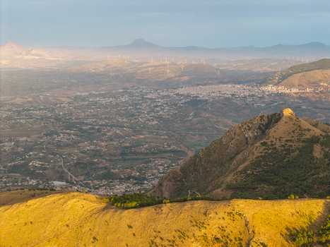 Aerial view of the mountainous landscape of Sicily near Palermo featuring rolling hills golden sunlight and distant wind turbines in Palermo Sicily Italy. Aerial view of the mountainous landscape of Sicily near Palermo featuring rolling hills golden sunlight and distant wind turbines in Palermo Sicily Italy.