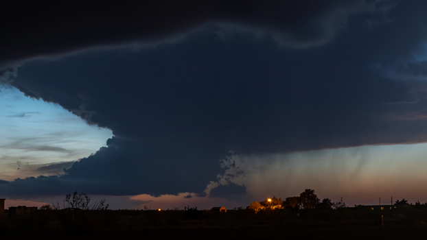 View of a massive dark storm cloud formation at dusk with rain shafts and dramatic lighting over the landscape in Oklahoma City Oklahoma United States.