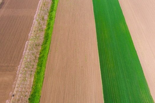 Aerial view of agricultural fields with alternating strips of brown soil and vibrant green crops in Bulgaria. Aerial view of agricultural fields with alternating strips of brown soil and vibrant green crops in Bulgaria.