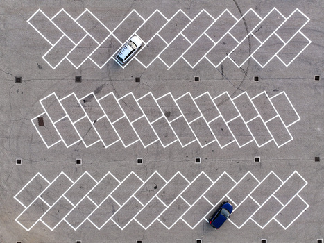 Aerial view of a parking lot with white diagonal lines and two cars parked on the asphalt in Borgo d Ale Piedmont Italy.