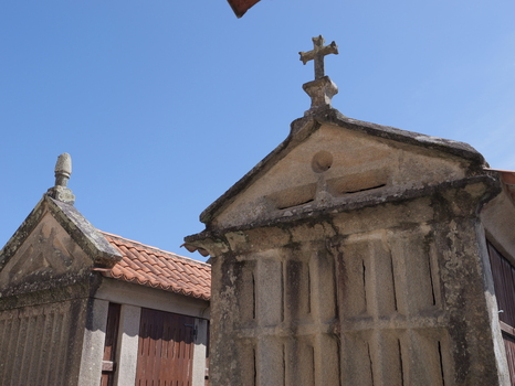 View of traditional stone granaries with crosses on top and tiled roofs under a clear blue sky in Combarro Pontevedra Spain.