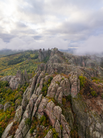 Aerial view of the unique sandstone and conglomerate rock formations of the Belogradchik Rocks surrounded by vibrant autumn foliage under a cloudy sky in Belogradchik Vidin Bulgaria. Aerial view of the unique sandstone and conglomerate rock formations of the Belogradchik Rocks surrounded by vibrant autumn foliage under a cloudy sky in Belogradchik Vidin Bulgaria.