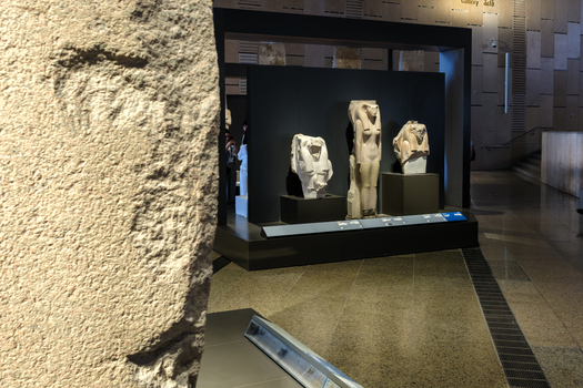 Giza Egypt 16 May 2026 View of ancient Egyptian statues displayed in a modern gallery at the Grand Egyptian Museum with stone walls and polished floors.