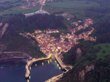 Aerial view of the illuminated coastal village nestled in a valley by the sea at dusk Cudillero Asturias Spain. Aerial view of the illuminated coastal village nestled in a valley by the sea at dusk Cudillero Asturias Spain.