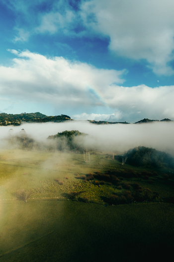 Aerial view of the rolling green hills and misty landscape near Puwheke Beach on the Karikari Peninsula Northland Region New Zealand.