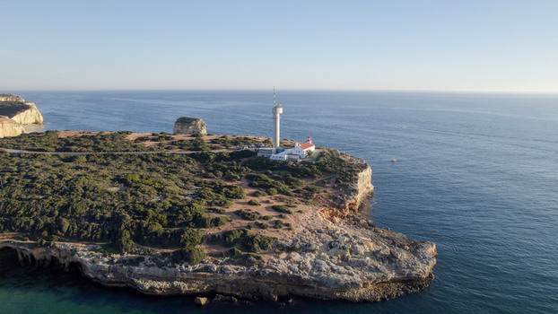 Aerial view of the Ponta do Altar Lighthouse situated on the rugged coastal cliffs overlooking the Atlantic Ocean in Ferragudo Faro District Portugal.