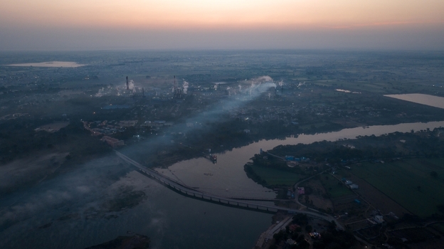 Aerial view of the industrial complex with smoking chimneys situated along the river at sunset in Nagda Madhya Pradesh India. Aerial view of the industrial complex with smoking chimneys situated along the river at sunset in Nagda Madhya Pradesh India.