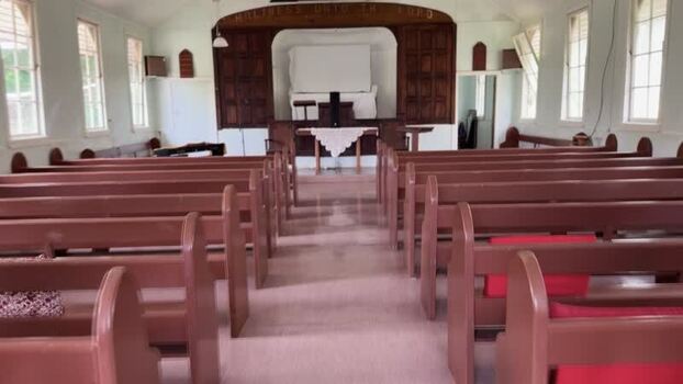 Aerial view of the rustic church interior where warm wooden pews stand in quiet anticipation beneath the soft glow of natural light Kingston Jamaica.