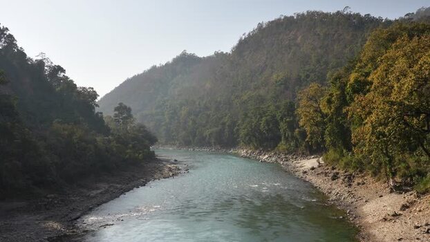 View of a wide river flowing through green mountain valleys Nepal.
